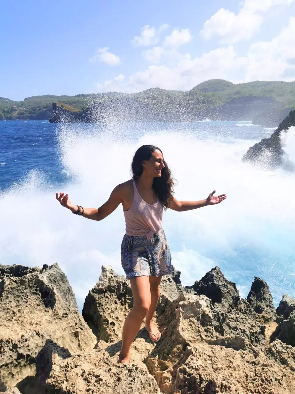 Christina Lefkati integrative therapist standing on rocks by ocean waves in Bali